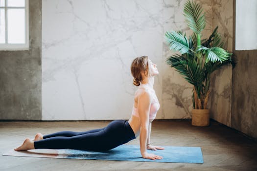 Woman in yoga pose on mat, exercising indoors with natural light and plant decor.