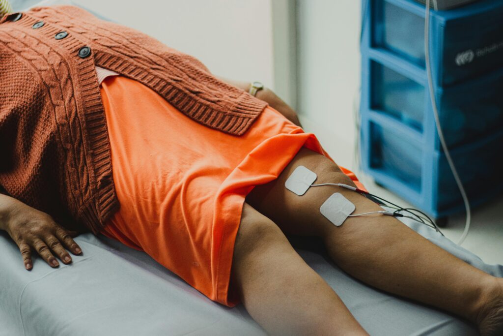 Close-up of a woman's legs during an electrical therapy session in a hospital setting.